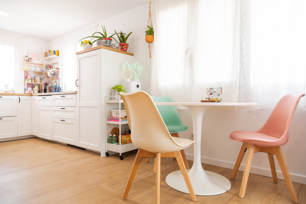 Comedor con sillas multicolores y ventana con cortinas