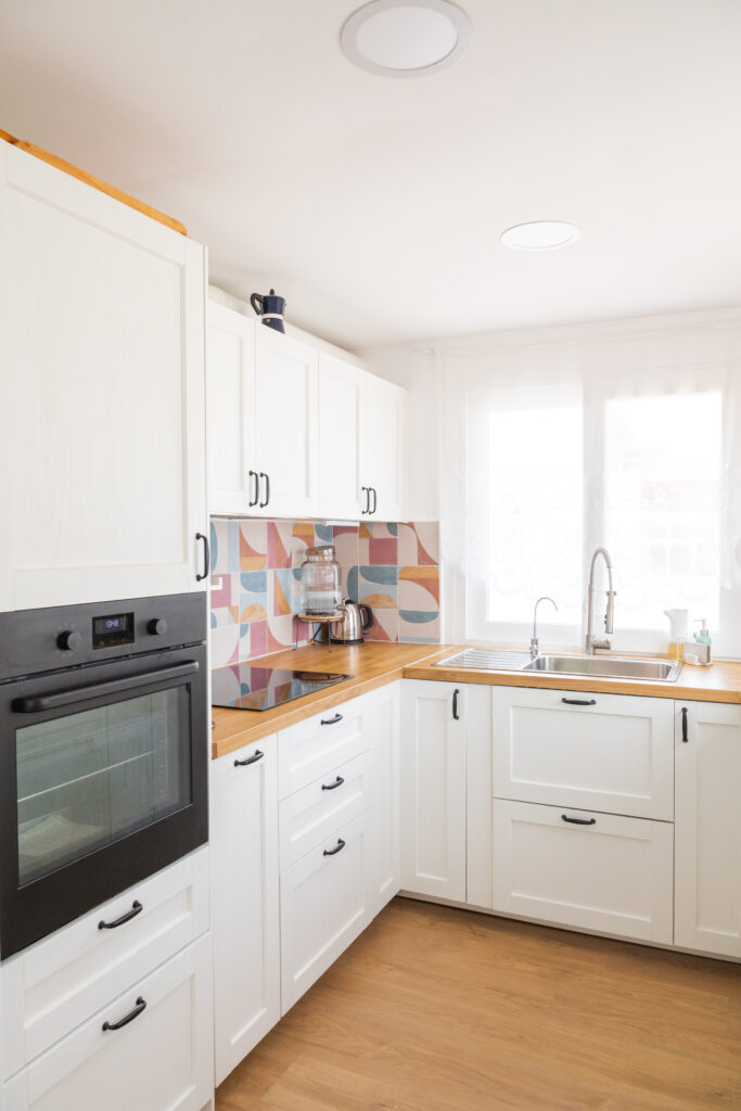 cocina blanca con azulejos de colores y ventana